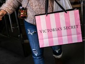 A customer carries a shopping bag while exiting a Victoria's Secret store.