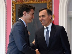 (FILES) In this file photo taken on November 20, 2019, Prime Minister Justin Trudeau shakes hands with Minister of Finance Bill Morneau during a ceremony at Rideau Hall in Ottawa.