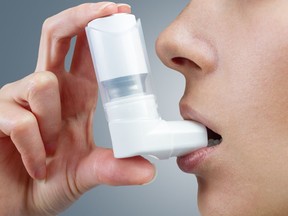 Woman uses an inhaler during an asthma attack, close-up