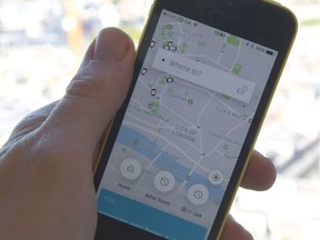 A man holds a smartphone showing the app for ride-sharing cab service Uber.