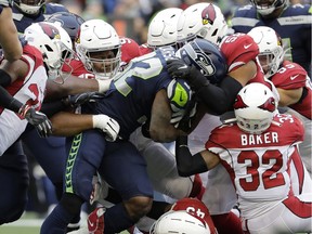 Seattle Seahawks running back Chris Carson (32) is tackled by Arizona Cardinals strong safety Budda Baker (32) and middle linebacker Jordan Hicks (58) during the first half of an NFL football game, Sunday, Dec. 22, 2019, in Seattle.