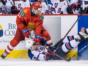 Russia's Vasili Podkolzin, left, checks United States' Logan Cockerill during first period semifinal IIHF world junior hockey championship action in Vancouver, on Friday January 4, 2019.