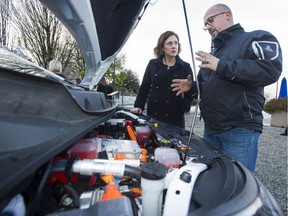 Automotive service technician Manoli Paterakis shows Energy Minister Michelle Mungall the working end of an electric car.