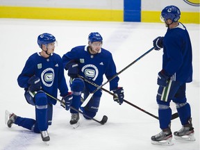 Vancouver Canucks Elias Pettersson, left, Quinn Hughes and Bo Horvat chat during a 2019 practice at Rogers Arena.