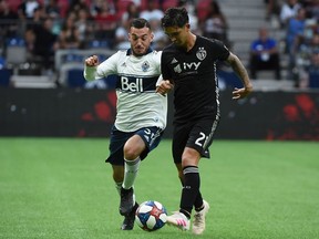 Vancouver Whitecaps midfielder Russell Teibert (left) vies for the ball against Felipe Gutierrez of Sporting KC during an MLS game last July at B.C. Place Stadium. The Whitecaps and Sporting KC will open their 2020 MLS season at B.C. Place Stadium on Feb. 29