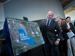 B.C. Premier John Horgan unveils a satellite image map showing where a new hospital will be built in Surrey, at an announcement on Dec. 9, 2019.