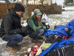 UGM spokesman Jeremy Hunka (left) and outreach worker Stephen Kastlison talk to a homeless man living under tarp only a block from Highway 1 in Abbotsford.