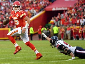 KANSAS CITY, MISSOURI - JANUARY 12:  Quarterback Patrick Mahomes #15 of the Kansas City Chiefs out runs J.J. Watt #99 of the Houston Texans during the AFC Divisional playoff game at Arrowhead Stadium on January 12, 2020 in Kansas City, Missouri.