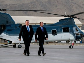 In this file photo taken on June 25, 2019, Secretary of State Mike Pompeo, left, walks from a helicopter with U.S. Ambassador to Afghanistan John Bass,as Pompeo returns to his plane after an unannounced visit to Kabul, Afghanistan.