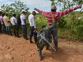 Members of the Revolutionary Armed Forces of Colombia (FARC) frisk people at a checkpoint in the Colombian southern department of Caqueta in May 2012. FARC demobilized in 2016 after reaching a peace deal with the Colombian government.