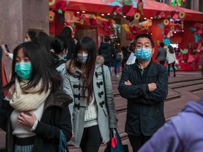 People wearing masks stand on a street in a shopping district in Hong Kong on Jan. 26, 2020, as a preventative measure following a coronavirus outbreak which began in the Chinese city of Wuhan.