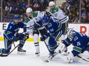 Rookie Quinn Hughes, in one of his first NHL games last season, helps goalie Jacob Markstrom corral the puck while veteran blue-line partner Luke Schenn (far left) ties up the Dallas Stars’ John Klingberg at Rogers Arena. Hughes credits Schenn with keeping things calm during his initial adjustment to the NHL.