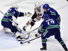 Canucks goalie Jacob Markstrom, defenceman Quinn Hughes and winger Brock Boeser try to squeeze out Chicago Blackhawk David Kampf (64) during their Jan. 2, 2020 game at Rogers Arena.