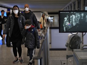 Health surveillance officer use temperature scanner to monitor passengers arriving at Hong Kong International Airport in Hong Kong Saturday, Jan. 25, 2020.