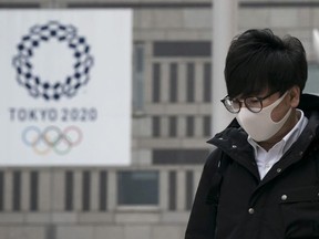 A pedestrian wearing a face mask walks past a banner promoting the upcoming Tokyo 2020 Olympic and Paralympic Games outside the Tokyo Metropolitan Government building on February 26, 2020 in Tokyo, Japan.