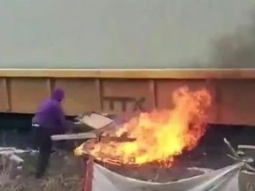 A protester sets fire by tracks as a train passes. (Twitter)