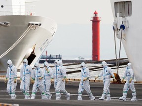 Men wearing protective gear are seen near the cruise ship Diamond Princess, where dozens of people have tested positive for coronavirus, Feb. 7, 2020.