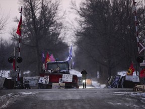 A protester looks through a pair of binoculars from the closed train tracks in Tyendinaga, near Belleville, Ont., on Sunday Feb.23, 2020. The rail blockade is in support of the Wet'suwet'en who oppose work on a pipeline in northern B.C.