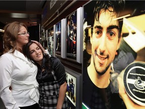 Suzanne Boucher, left, mother of the late Vancouver Canucks' defenceman Luc Bourdon, embraces Charlene Ward (Luc's girlfriend at the time), as they look at his photo on a tribute wall unveiled by the Canucks on Oct. 9, 2008. Bourdon was killed in a motorcycle collision near his home town of Shippagan, N.B.