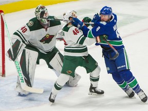 J.T. Miller battles with  Jared Spurgeon in front of Wild goalie Devan Dubnyk.