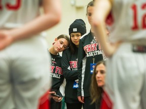 Alanna Noble leans her head on Terry Fox secondary’s Karin Khuong during a break in play at the B.C. high school girls basketball provincial championships at the Langley Events Centre.