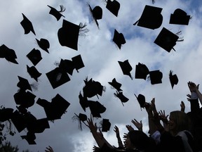 Students throw their mortarboards in the air during their graduation