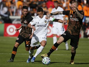 Los Angeles Galaxy striker Chicharito brings the ball up the field between Tomas Martinez and Kiki Struna of the Houston Dynamo during the first half at BBVA Stadium on last Saturday in Houston, Texas.
