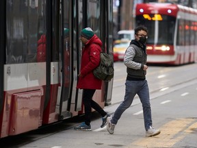 A man in a mask gets off a street car in downtown Toronto, Ontario on March 24, 2020. AFP photo)