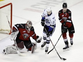 Giants netminder Trent Miner tracks the puck as Bowen Byram tries to tie up Royals forward Sean Gulka.