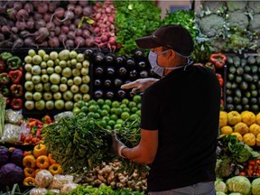 A man wearing a face mask as a preventive measure against the spread of the new coronavirus, COVID-19, buys groceries.