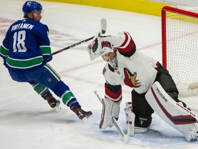 Arizona Coyotes goalie Darcy Kuemper makes a glove save on Jake Virtanen.