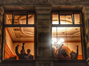 Members of the Indigenous Youth group of protesters gesture from inside the B.C. legislature on Wednesday night.