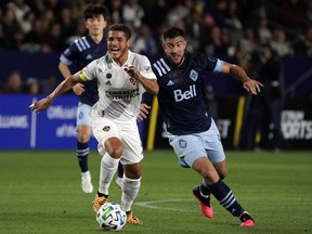 LA Galaxy midfielder Jonathan dos Santos (left) drives the ball against Vancouver Whitecaps forward Lucas Cavallini (9) in the first half at Dignity Health Sports Park.