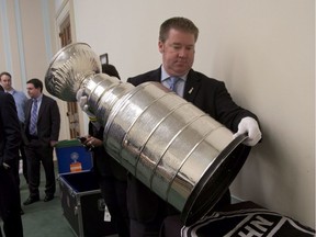 Mike Bolt, the keeper of the Stanley Cup, places the Stanley Cup hockey trophy on a side table, on Capitol Hill in Washington, Wednesday, April 24, 2013, before a congressional hockey caucus briefing to discuss state of hockey including instructional hockey and safety in youth sports.
