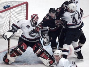 Canucks Dave Babych takes out Phoenix Coyotes Mike Gartner in front of goalie Sean Burke at GM Place in Vancouver. on Jan. 21, 1998.