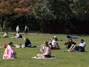 Vancouverites enjoy the sunshine while sitting at Kits Beach in Vancouver, BC, April, 13, 2020.