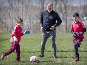 Mike Smith kicks a soccer ball with children Sofya and James in Laval, north of Montreal, on Wednesday. Smith says he's out $2,600 after a soccer academy associated with a Spanish club was cancelled and the owners declared bankruptcy.