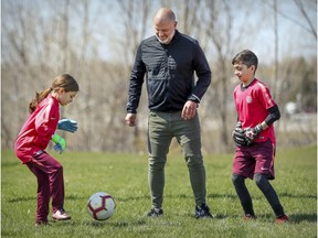 Mike Smith kicks a soccer ball with children Sofya and James in Laval on May 13, 2020. Smith is out thousands of dollars after a soccer academy linked to Spanish giant FC Barcelona was cancelled and the owners declared bankruptcy.