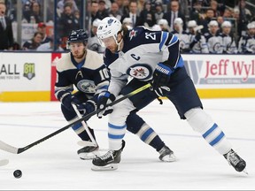 Winnipeg Jets centre Blake Wheeler (26) grabs a loose puck as Columbus Blue Jackets centre Alexander Wennberg (10) trails the play at Nationwide Arena.