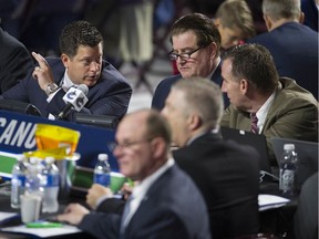 Scouting director Judd Brackett, left, talks to Vancouver Canucks' GM Jim Benning, centre, and AGM John Weisbrod during the 2019 NHL Entry Draft at Rogers Arena in Vancouver. Brackett wanted some conditions before accepting a two-year contract extension from the NHL club, but Benning refused to budge.