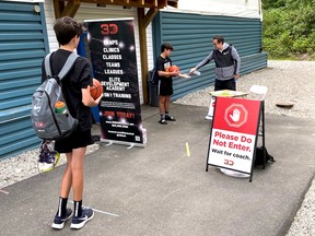 Thomas Staron, owner of 3D Basketball Academy, sanitizes the hands of his players as they enter the gym at Lions Gate Christian Academy in North Vancouver. The club is currently only allowed to do individual shooting and ball-handling drills under social distancing protocols.