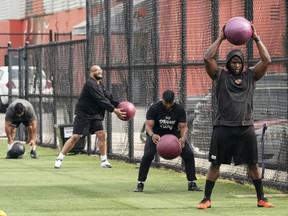Defensive tackle Claudell Louis, right, a small group of teammates throw medicine balls around during a workout at the B.C. Lions' practice facility in Surrey on Tuesday.