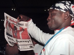 Surrey’s Olympic gold medal-winning wrestler Daniel Igali arrives home at Vancouver International Airport, checking out a copy of The Province on Oct. 3, 2000.