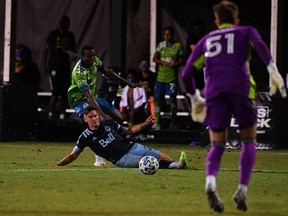 Ryan Raposo of the Vancouver Whitecaps makes a sliding tackle against Nouhou Tolo of the Seattle Sounders during their MLS is Back Tournament match on July 19 in Reunion, Fla.