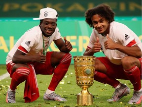 Bayern Munich's Canadian midfielder Alphonso Davies, left, and Bayern Munich's Dutch forward Joshua Zirkzee celebrate with the German Cup (DFB Pokal) trophy after winning the final match against Bayer 04 Leverkusen at the Olympic Stadium in Berlin on July 4, 2020.