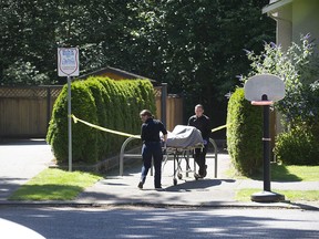 Attendants bring a body from a wooded area near 46A Avenue and 196A Street in Langley on Wednesday, July 15. The suspicious death was revealed by crews as they battled a small brush fire.
