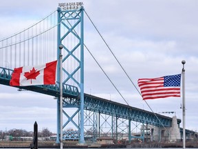 Canadian and American flags fly near the Ambassador Bridge at the Canada-USA border crossing in Windsor, Ont. on Saturday, March 21, 2020.