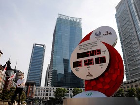 A man wearing a protective mask walks past a countdown clock for the Tokyo 2020 Olympic Games back in June.