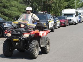 A police officer drives his quad on a street, Friday, July 10, 2020 in Saint-Apollinaire, Que. Police are continuing their search around a Quebec City suburb after they issued an Amber Alert Thursday for two young girls and their 44-year-old father who investigators believe disappeared following a highway car crash.