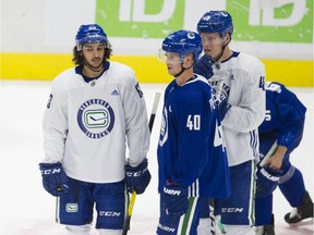 Jalen Chatfield (left) with Elias Pettersson and Olli Juolevi at Canucks practice in July.